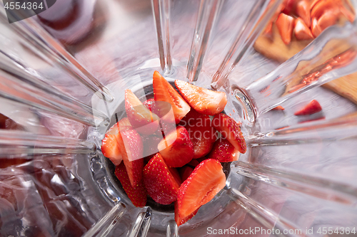 Image of Pieces of ripe strawberries in a blender bowl. Preparation of smoothies. Top view