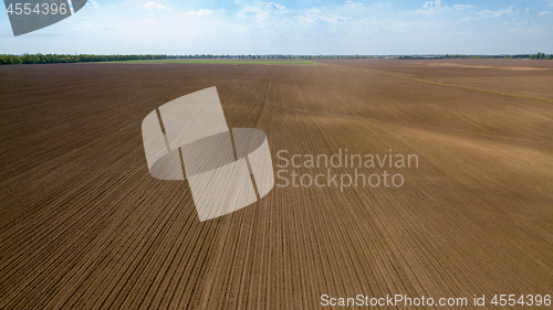 Image of Agricultural ploughed field and soil in spring against the blue sky. Photo from the drone