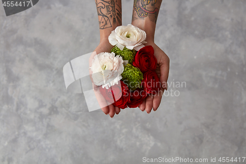 Image of girl with a tattoo on her hands holding a bouquet of flowers