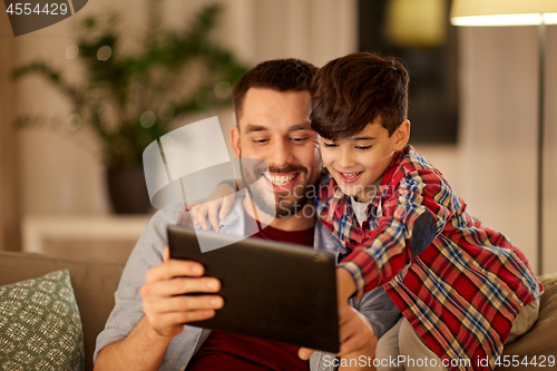 Image of father and son with tablet pc playing at home