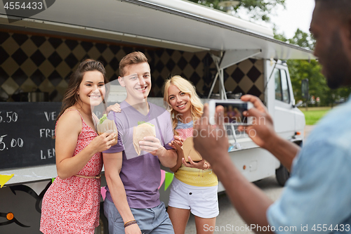 Image of man taking picture of friends eating at food truck