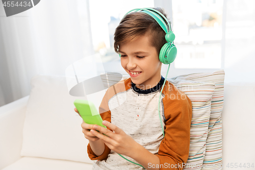 Image of happy boy with smartphone and headphones at home