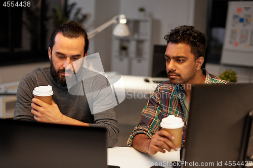 Image of creative team drinking coffee at night office