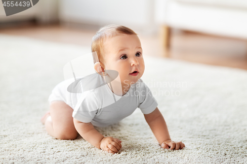 Image of little baby crawling on floor at home