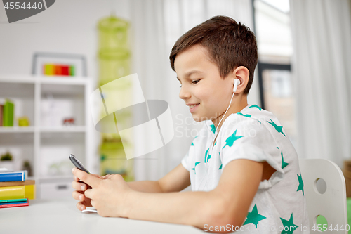 Image of boy in earphones listening to music on smartphone