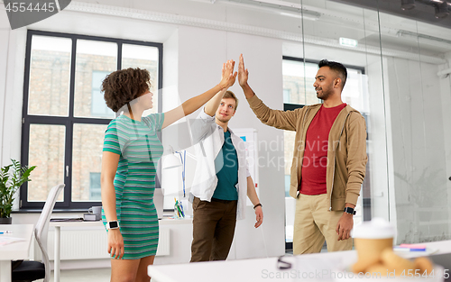 Image of happy creative team making high five at office