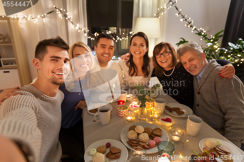 Image of happy family taking selfie at tea party at home