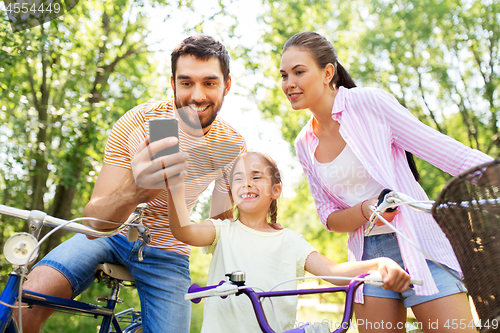 Image of family with smartphone and bicycles in summer park