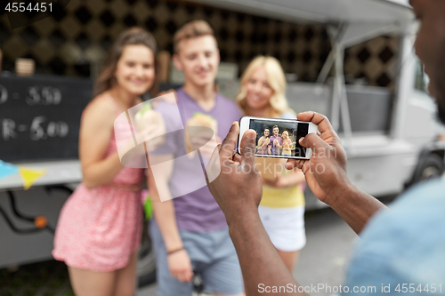 Image of man taking picture of friends eating at food truck