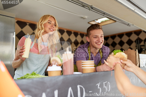 Image of happy sellers serving customers at food truck