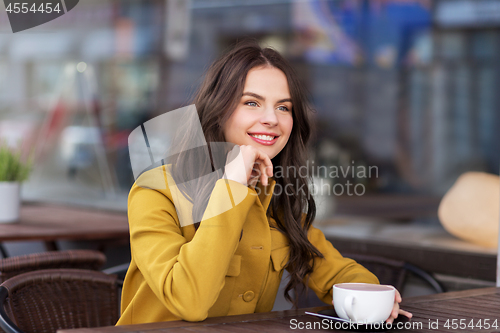 Image of teenage girl drinking hot chocolate at city cafe