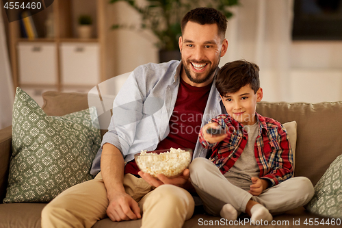 Image of father and son with popcorn watching tv at home