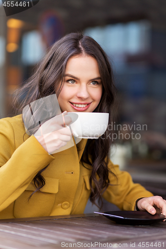 Image of teenage girl drinking hot chocolate at city cafe