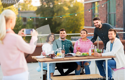 Image of happy friends photographing at rooftop party