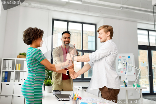 Image of happy creative team making high five at office