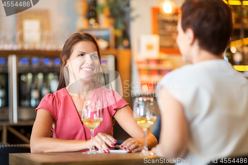 Image of happy women drinking wine at bar or restaurant