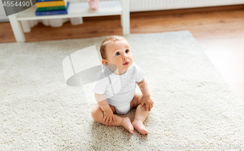 Image of baby sitting on floor at home and looking up