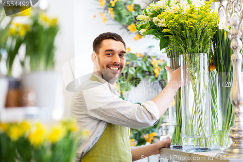 Image of happy florist man setting flowers at flower shop