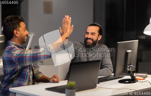 Image of creative team making high five at night office