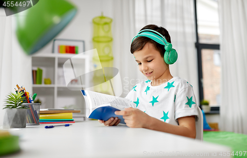 Image of boy in headphones with textbook learning at home