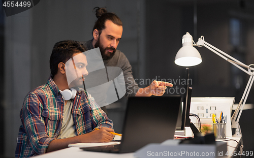 Image of creative team with computer working late at office