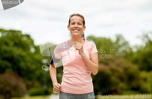 Image of woman with earphones add armband jogging at park