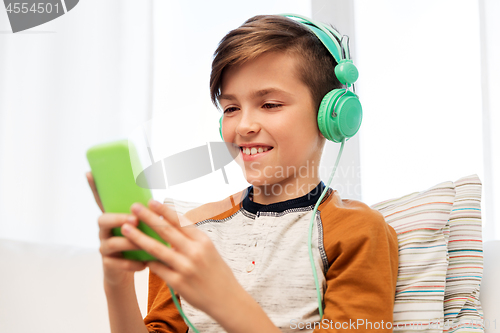 Image of happy boy with smartphone and headphones at home
