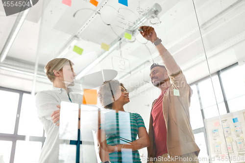 Image of happy creative team at office glass board