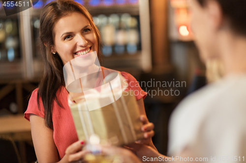 Image of woman receiving present from friend at restaurant