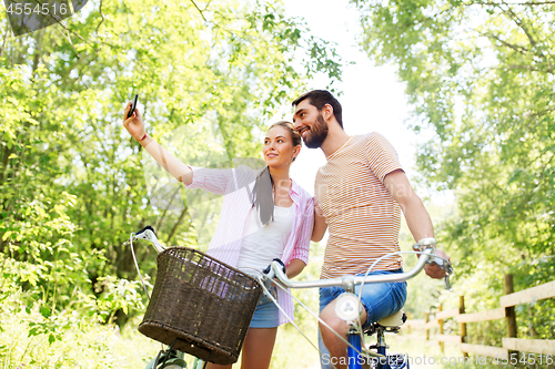 Image of couple with bicycles taking selfie by smartphone