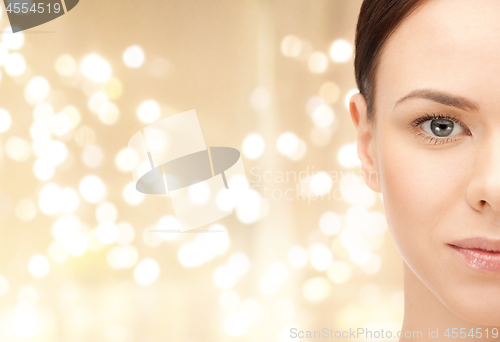 Image of half face of young woman over lights background