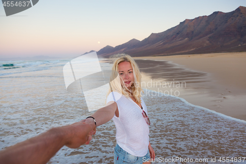 Image of Romantic couple holding hands on beach.