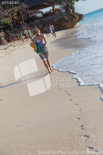 Image of Woman running on the beach in sunset.