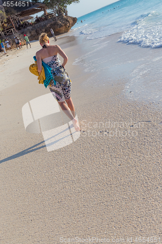 Image of Woman running on the beach in sunset.