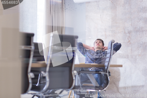 Image of young businessman relaxing at the desk