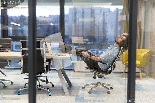 Image of young businessman relaxing at the desk