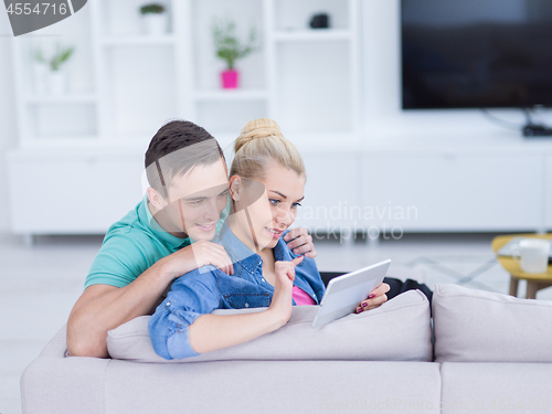 Image of couple relaxing at  home with tablet computers