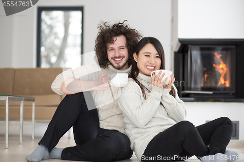 Image of happy multiethnic couple  in front of fireplace