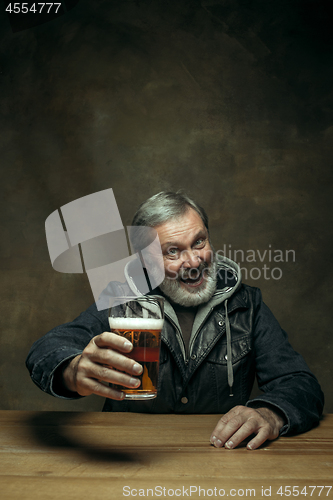 Image of Smiling bearded male drinking beer in pub