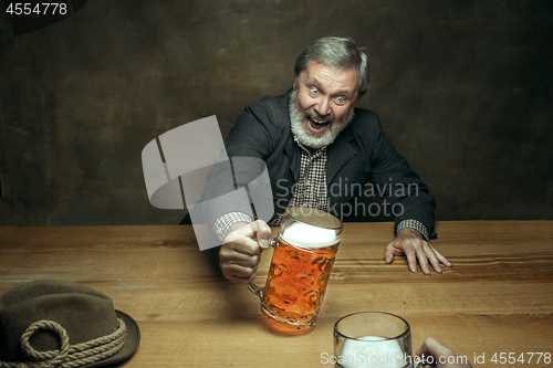 Image of Smiling bearded male drinking beer in pub