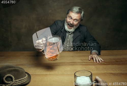 Image of Smiling bearded male drinking beer in pub