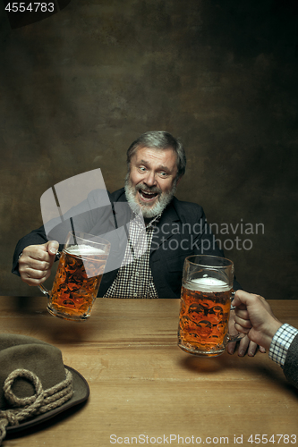 Image of Smiling bearded male drinking beer in pub