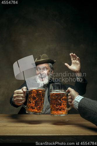 Image of Smiling bearded male drinking beer in pub