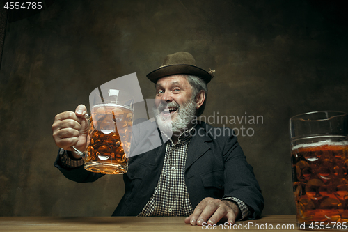 Image of Smiling bearded male drinking beer in pub