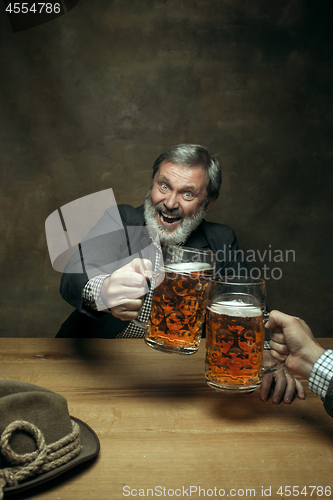 Image of Smiling bearded male drinking beer in pub