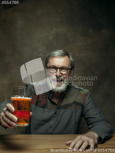 Image of Smiling bearded male drinking beer in pub