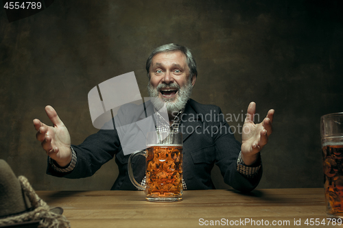 Image of Smiling bearded male drinking beer in pub