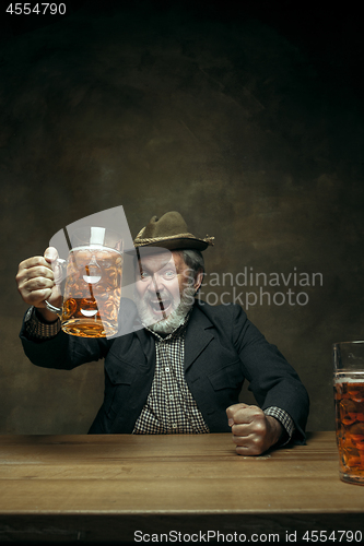 Image of Smiling bearded male drinking beer in pub