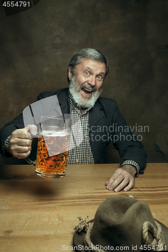 Image of Smiling bearded male drinking beer in pub