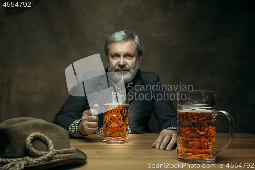 Image of Smiling bearded male drinking beer in pub